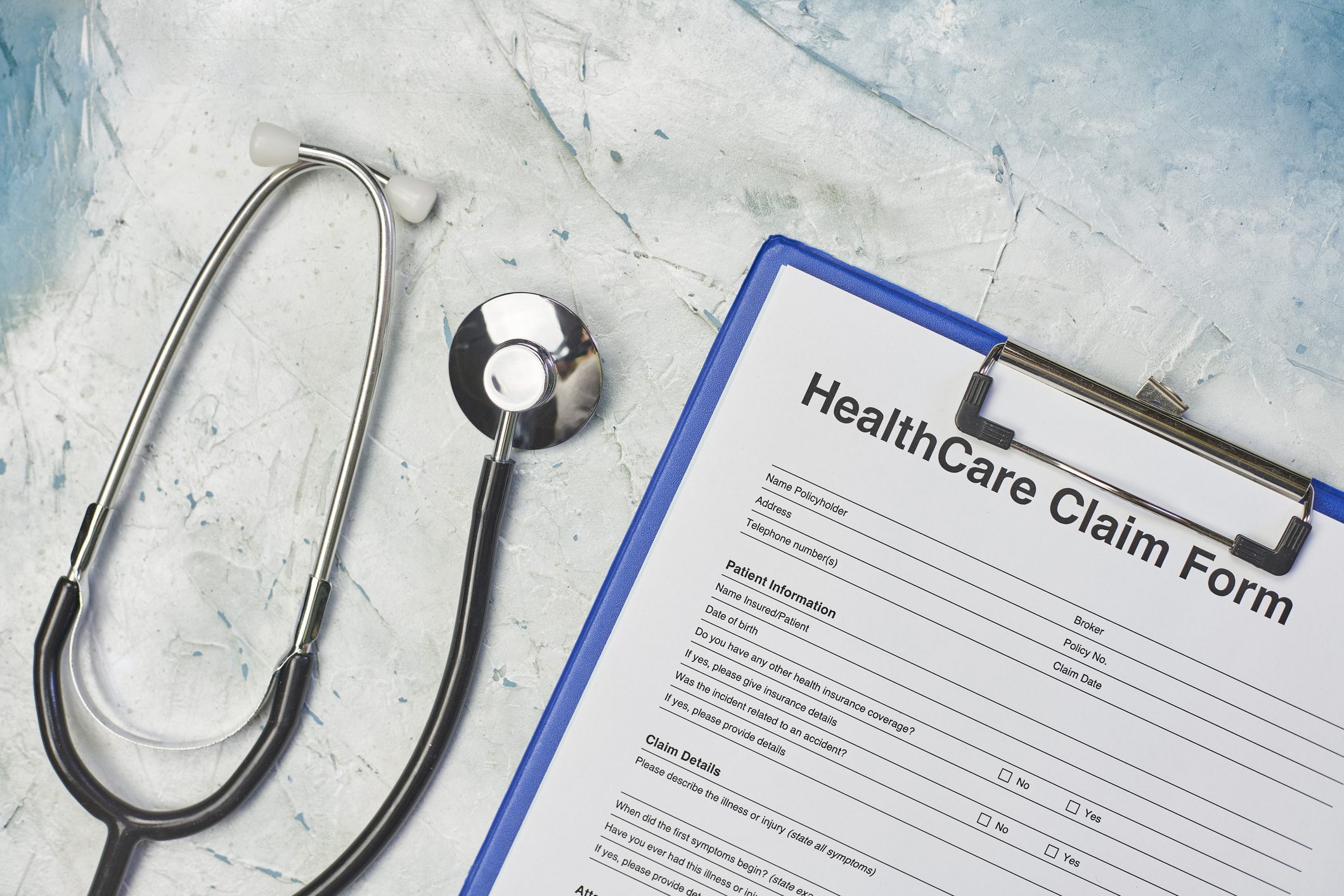 Healthcare claim form and stethoscope on table.