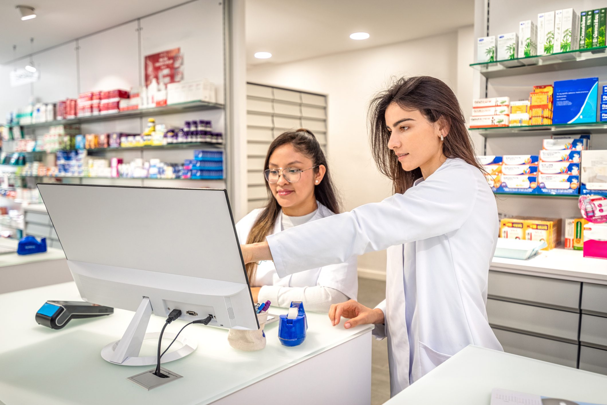 Pharmacists working together at computer counter.